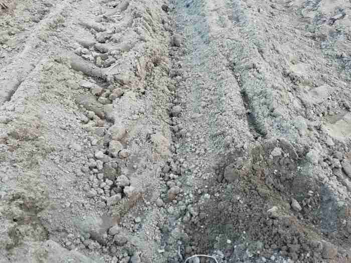 cultivated loam soil in drills in a field showing tractor tyre imprints 