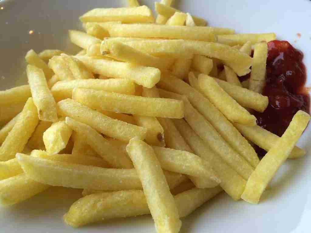 crispy yellow potato french fries on a plate with tomato sauce