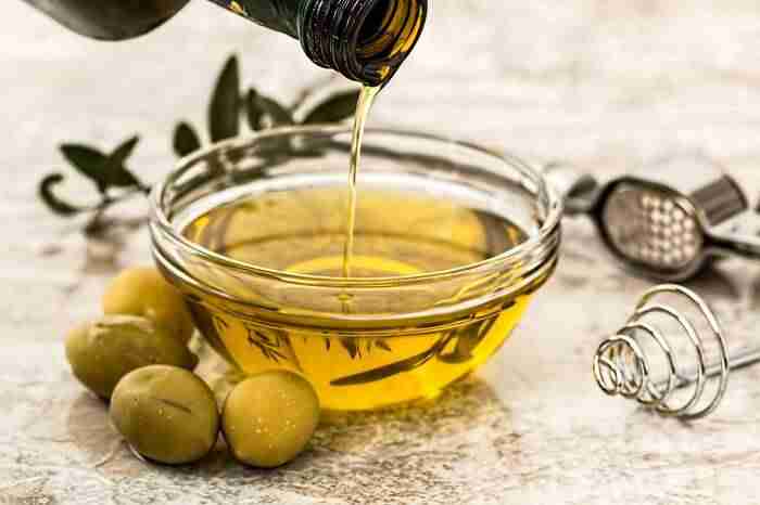 olive oil being poured out of a bottle into a glass bowl