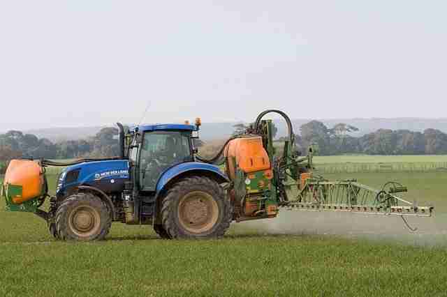 tractor and sprayer spraying crops